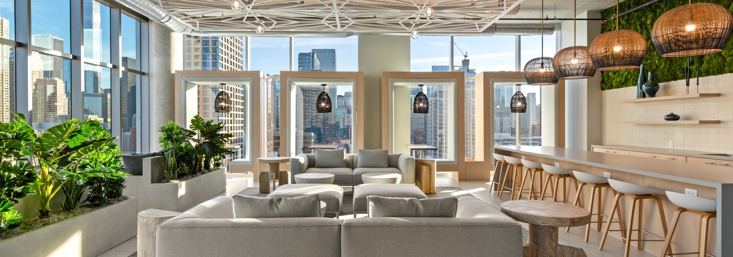 Neutral seating in AMLI 808 resident lounge with geometric decor on ceiling lined by floor to ceiling windows with city view