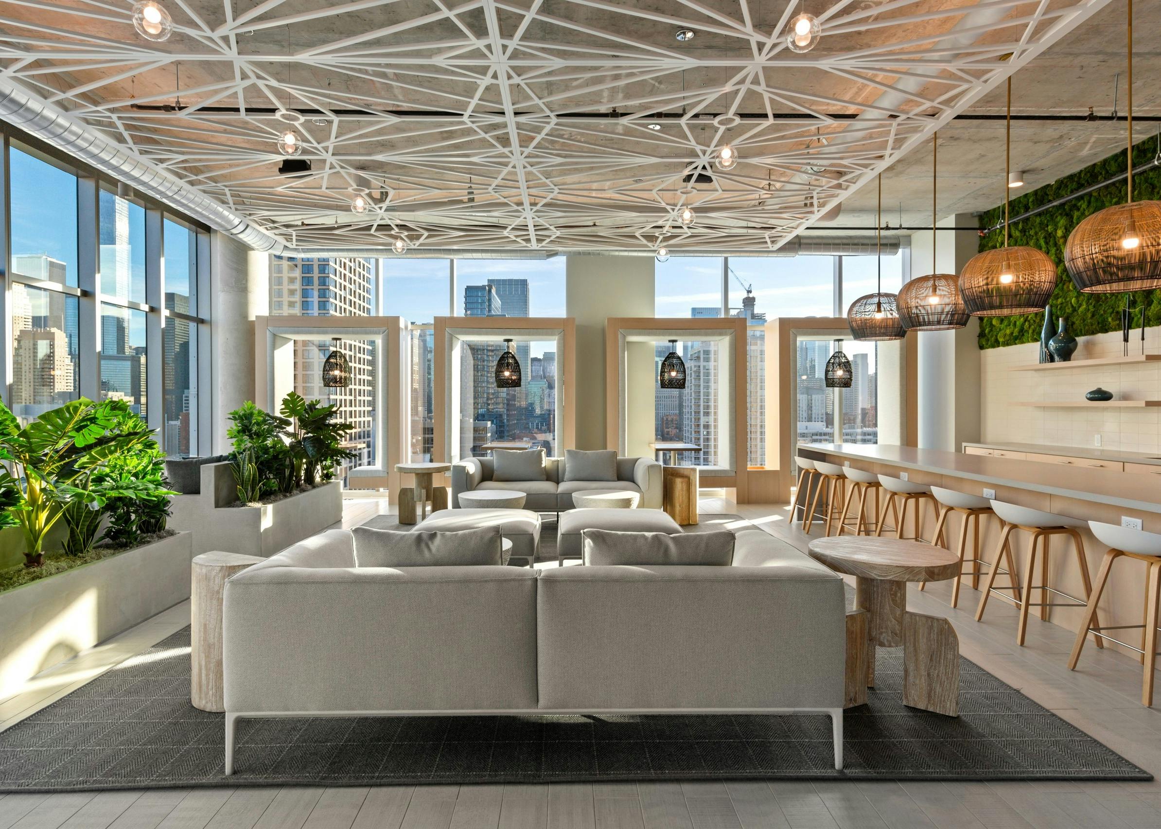 Neutral seating in AMLI 808 resident lounge with geometric decor on ceiling lined by floor to ceiling windows with city view