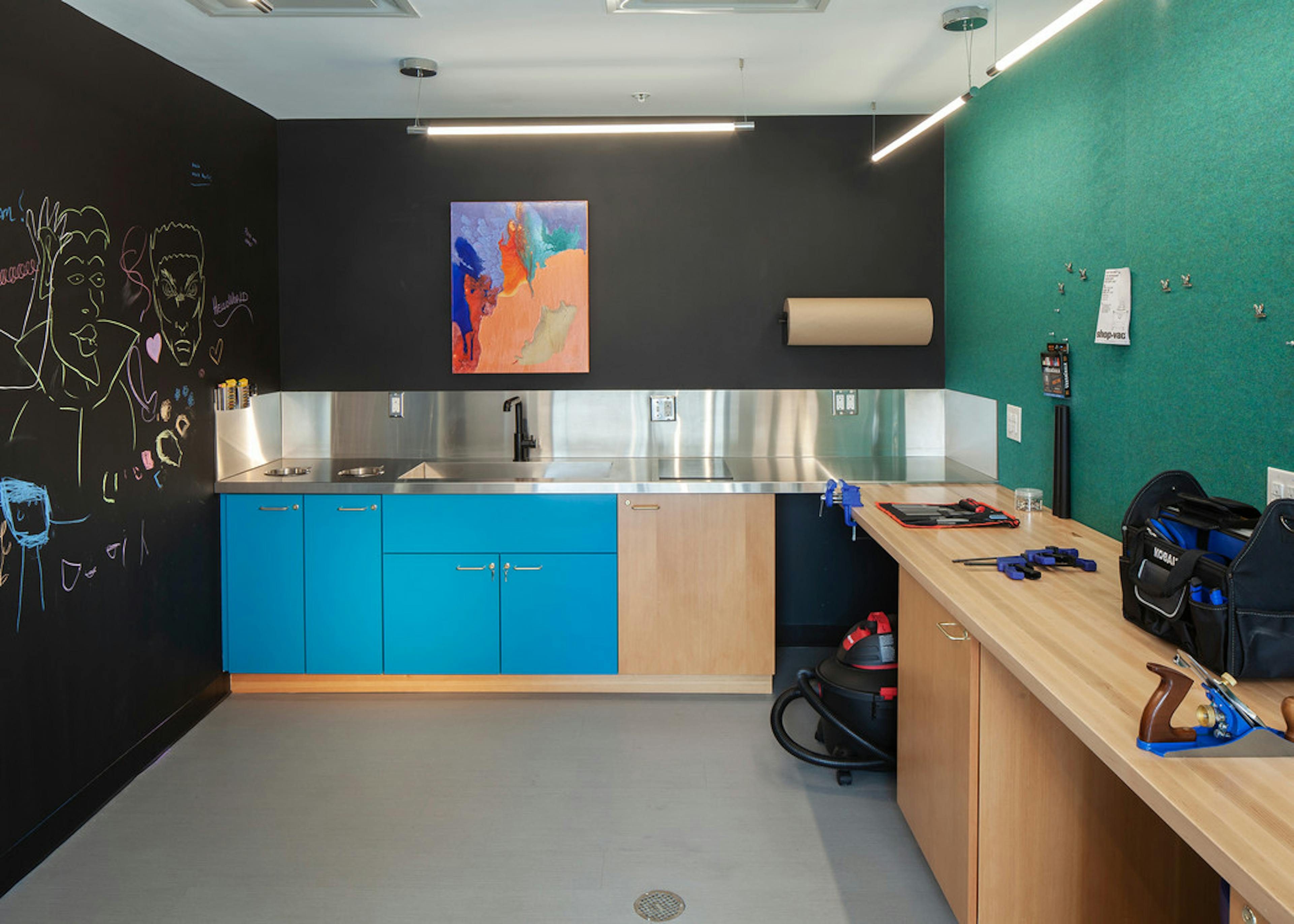 A DIY Maker Room at AMLI Riverfront Green apartments with work table and tool box as well as a large sink area with cabinets