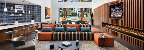 Interior view of clubhouse with various seating areas and fireplace at AMLI Uptown Orange apartments overlooking pool area
