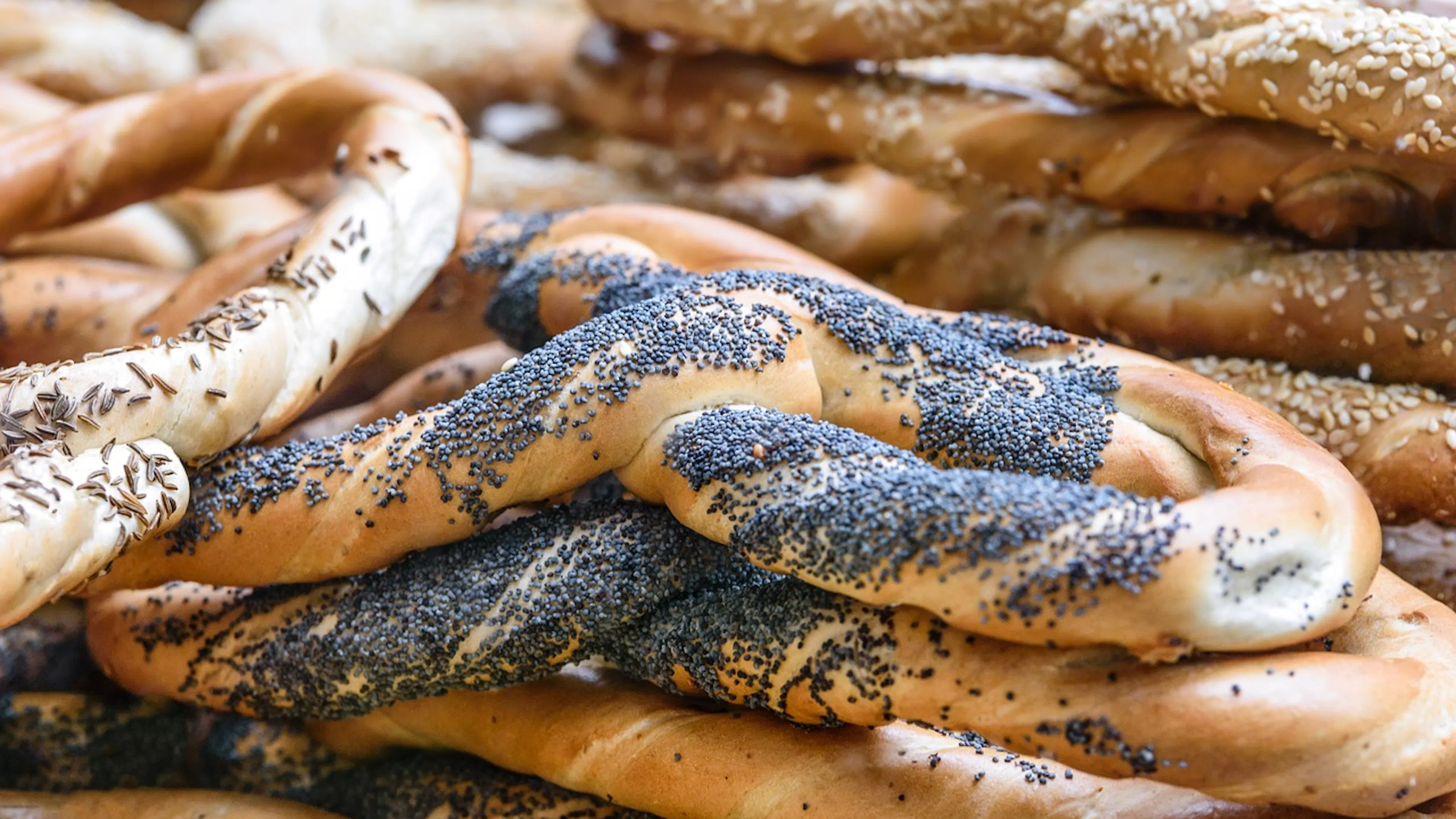 A stack of ring-shaped breads covered in sesame seeds and poppy seeds