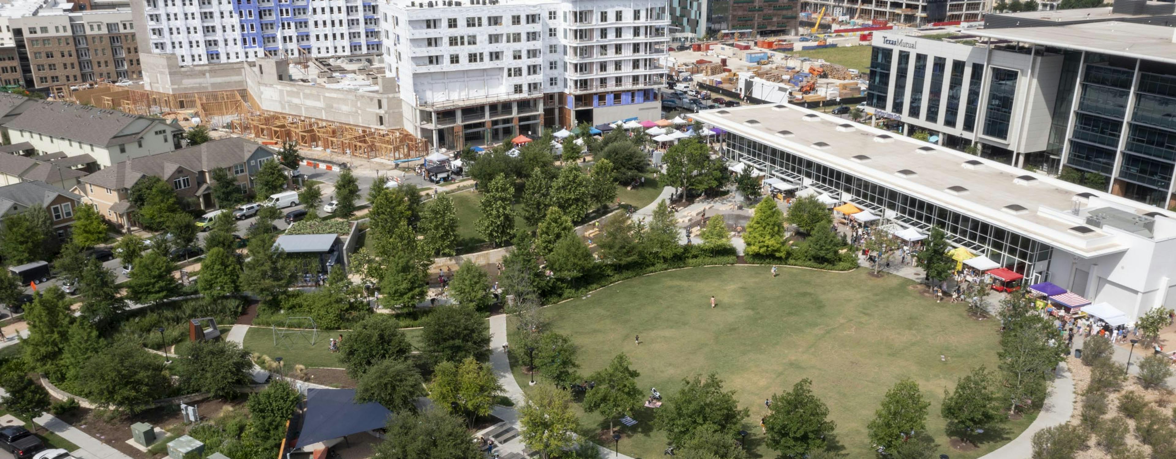 Aerial view during the day of Mary Elizabeth Branch Park including large grassy lawns and a playground shaded by trees