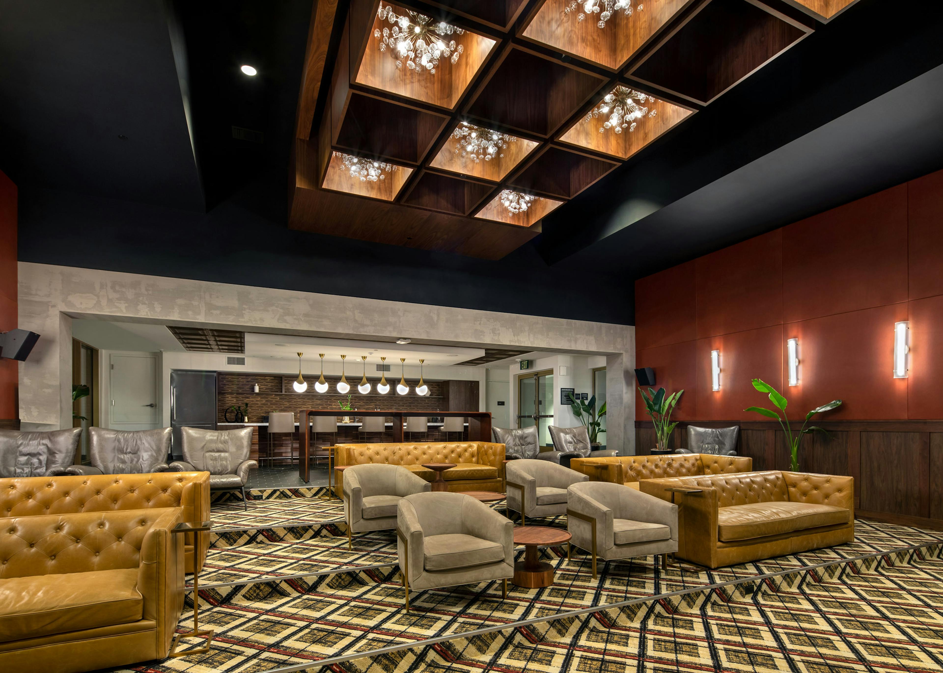 Interior of theatre room with ample lounge seating under a lit and decorative ceiling with chandeliers at AMLI Old Pasadena