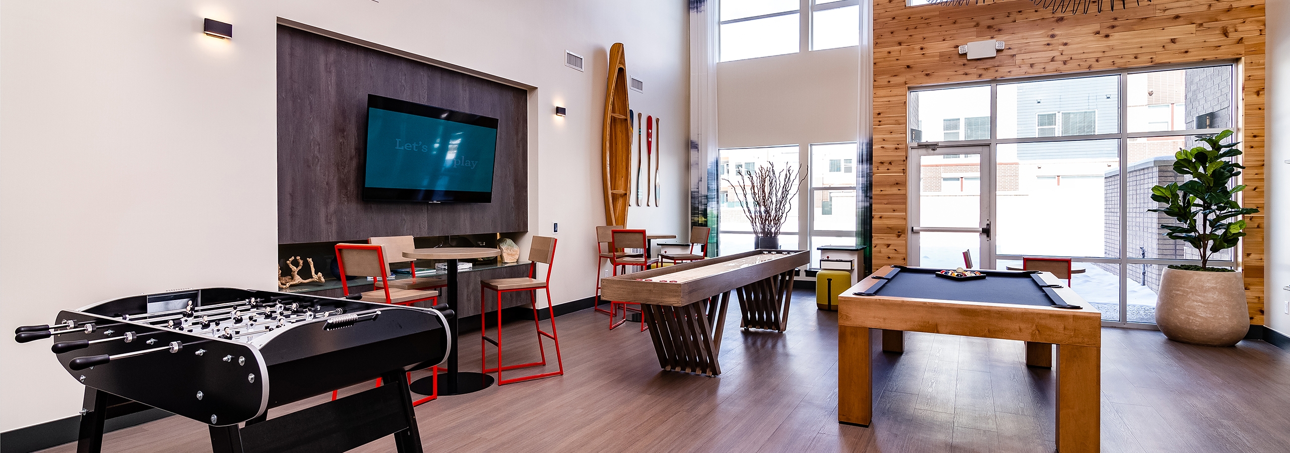 Interior of clubroom with shuffle board, pool table and foosball table and big screen TV at AMLI Littleton Village apartments