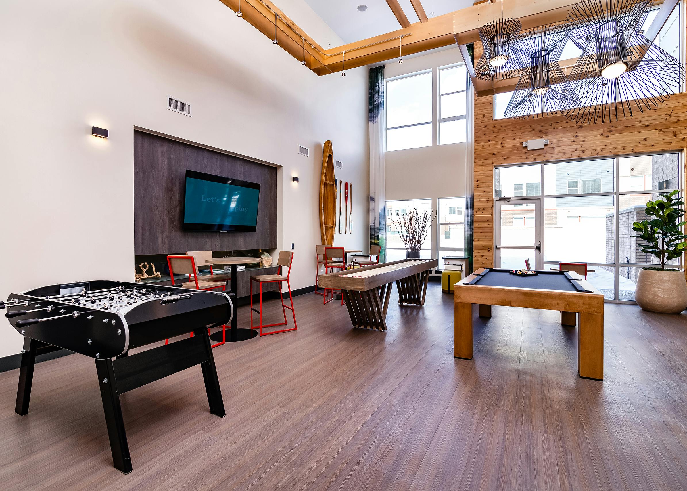 Interior of clubroom with shuffle board, pool table and foosball table and big screen TV at AMLI Littleton Village apartments