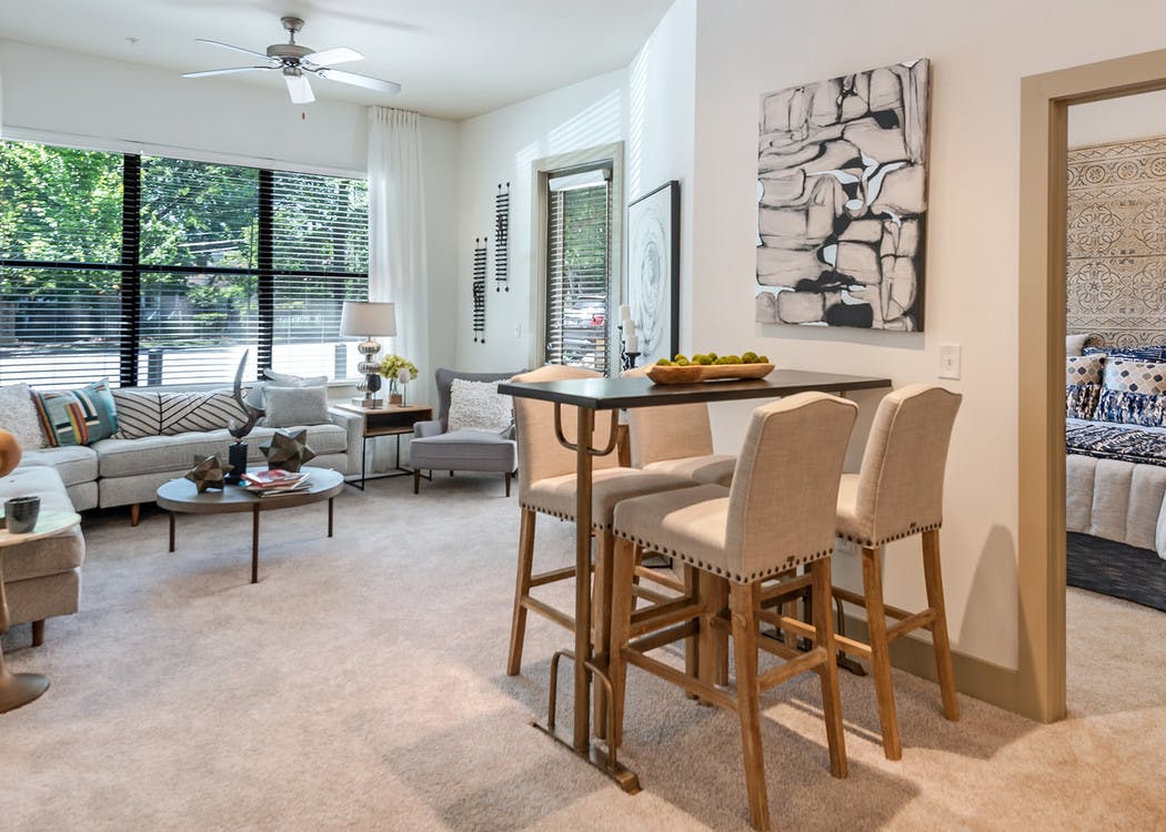 Interior of AMLI Parkside apartment living room with carpet and cream walls with a peek inside bedroom through open door