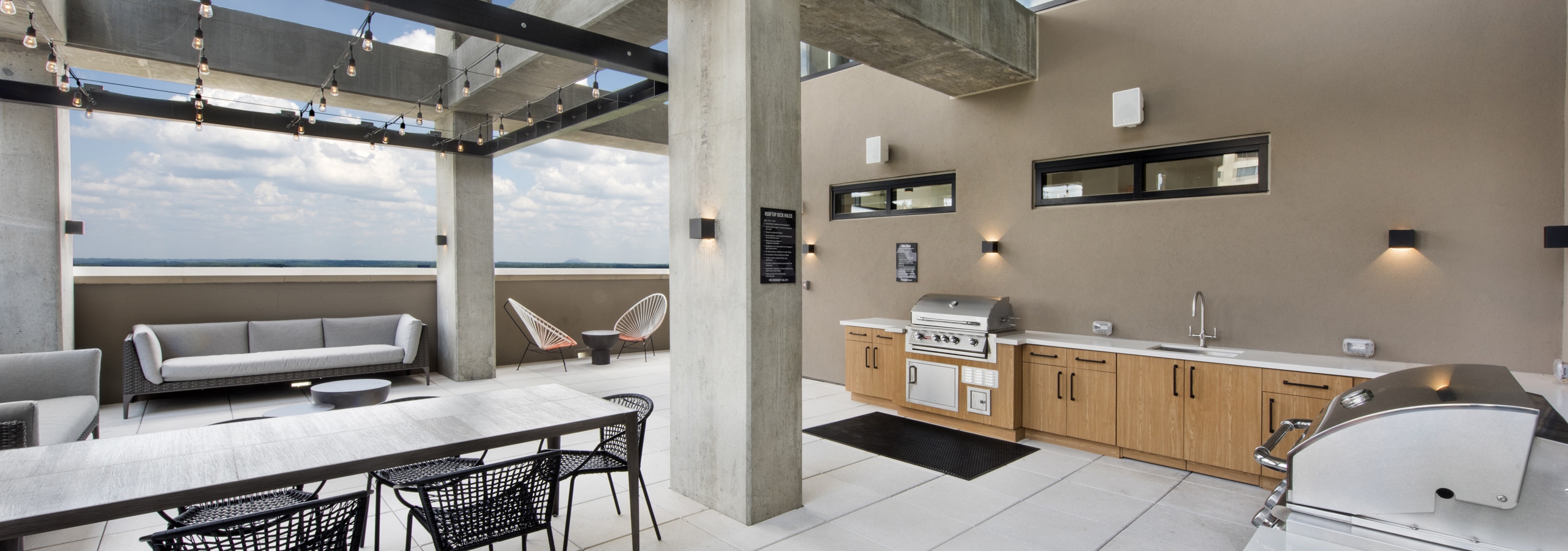 Outside view of AMLI Lenox rooftop with two grills and sink and lots of storage space with multiple seating areas