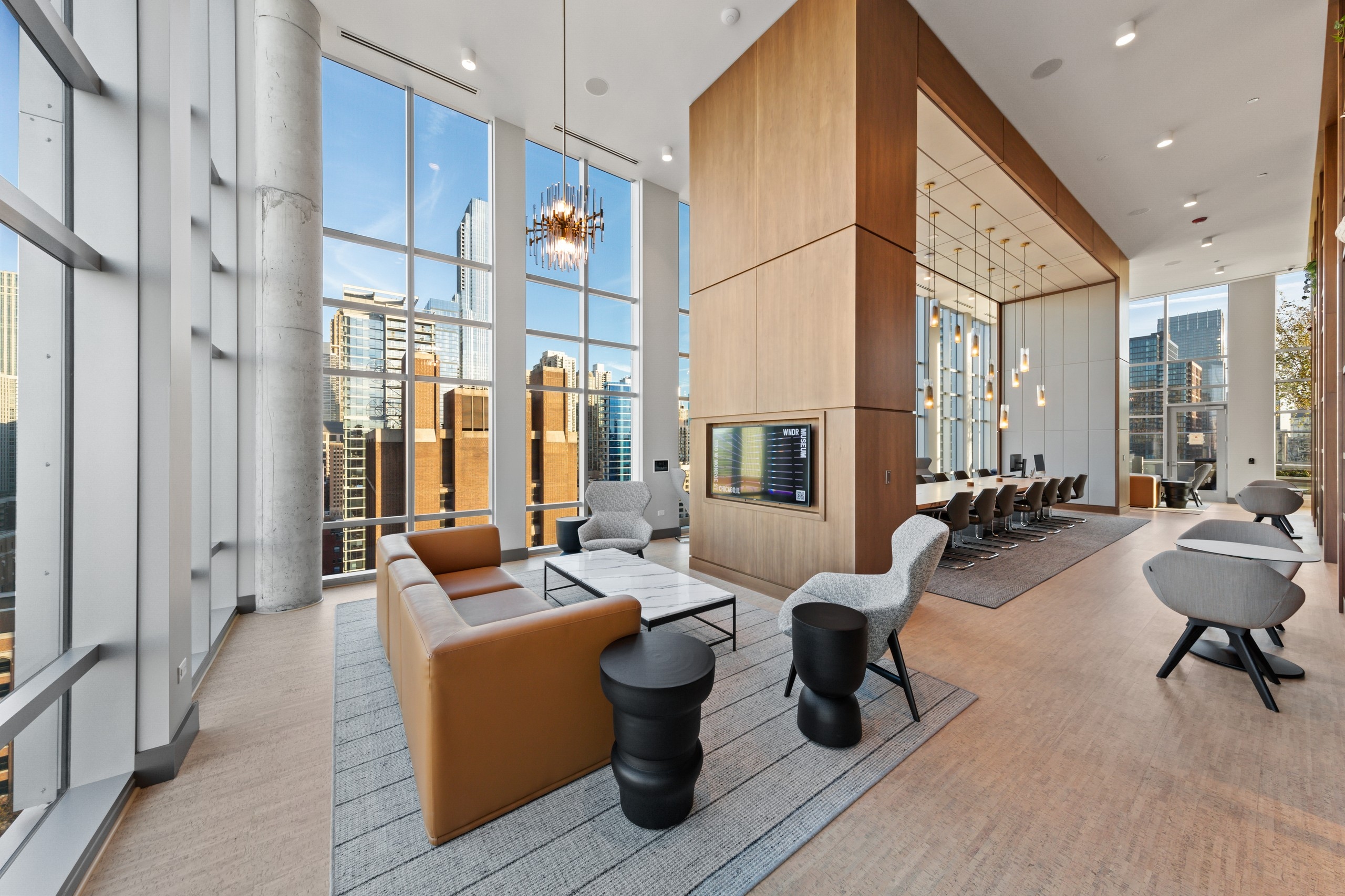Modern seating area in AMLI 808 work from home collab amenity space lined with bright windows and statement light fixtures