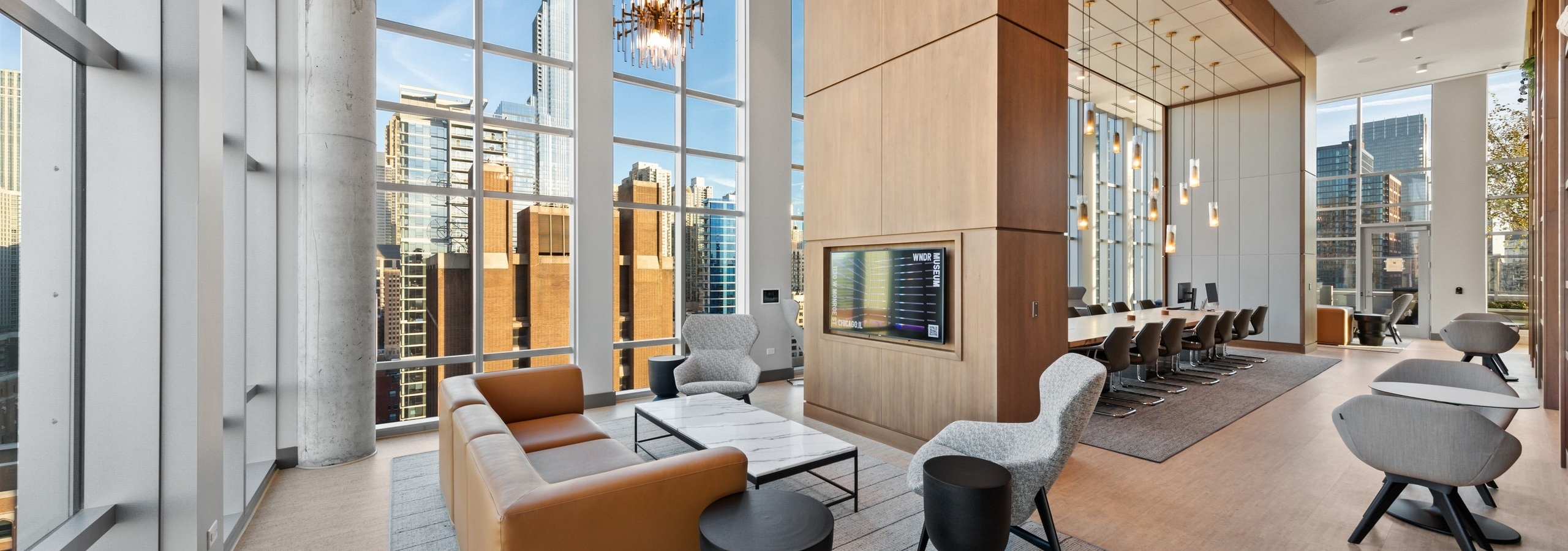 Modern seating area in AMLI 808 work from home collab amenity space lined with bright windows and statement light fixtures