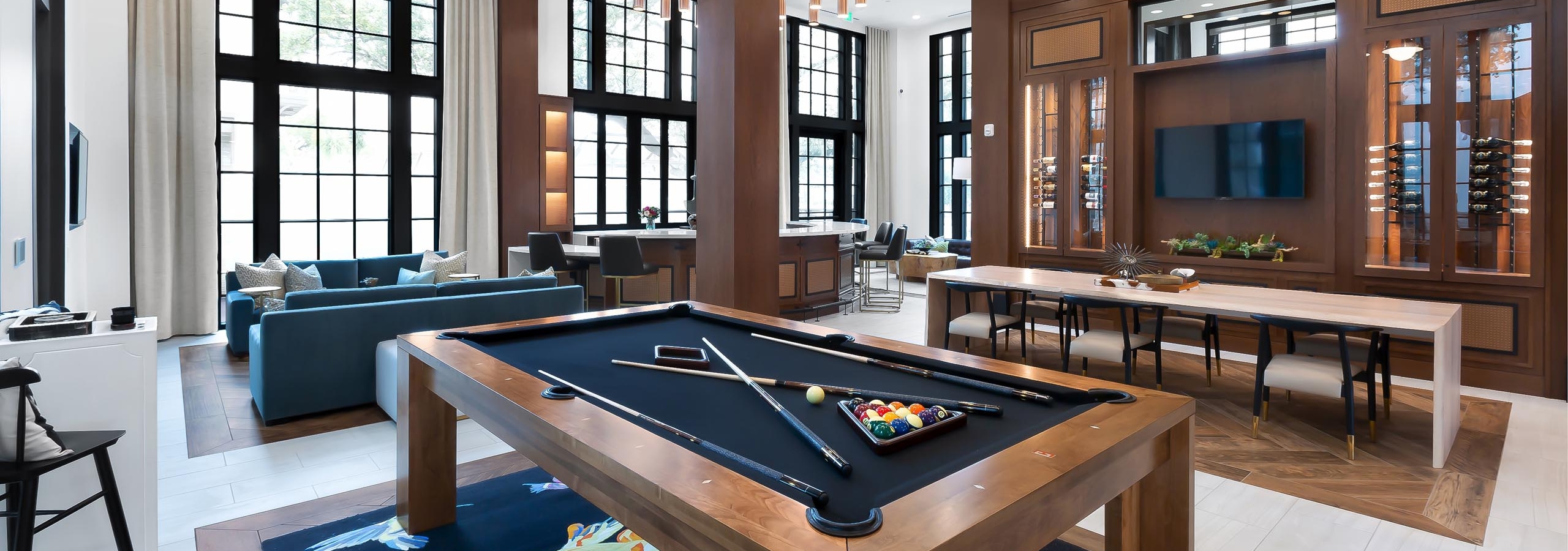 Resident lounge at AMLI Lakeline apartments with a wooden billiards table and a TV flanked by two wine storage cabinets