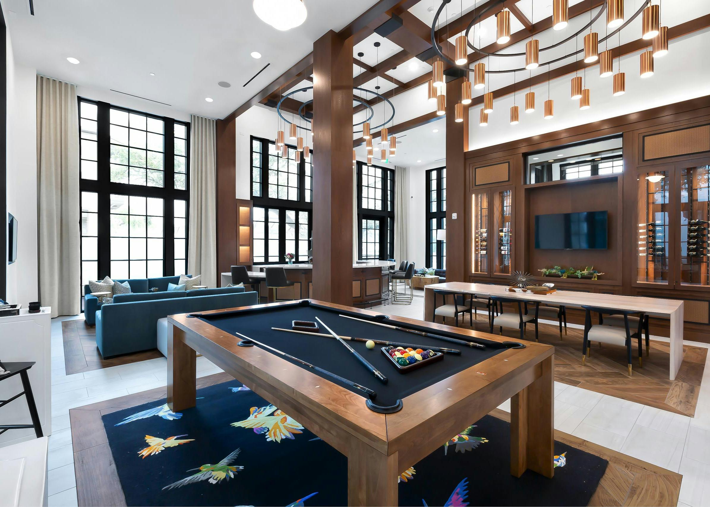 Resident lounge at AMLI Lakeline apartments with a wooden billiards table and a TV flanked by two wine storage cabinets