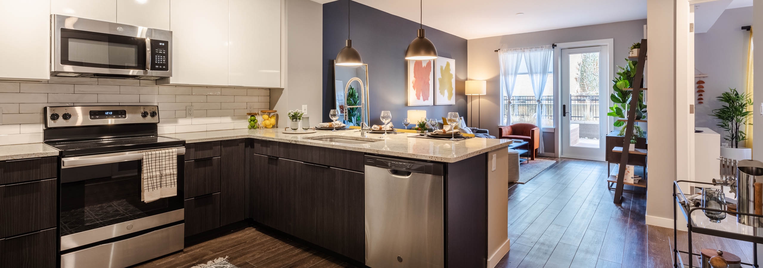 AMLI at Uptown living area with dark blue accent wall extending to eating area with view of modern kitchen in background