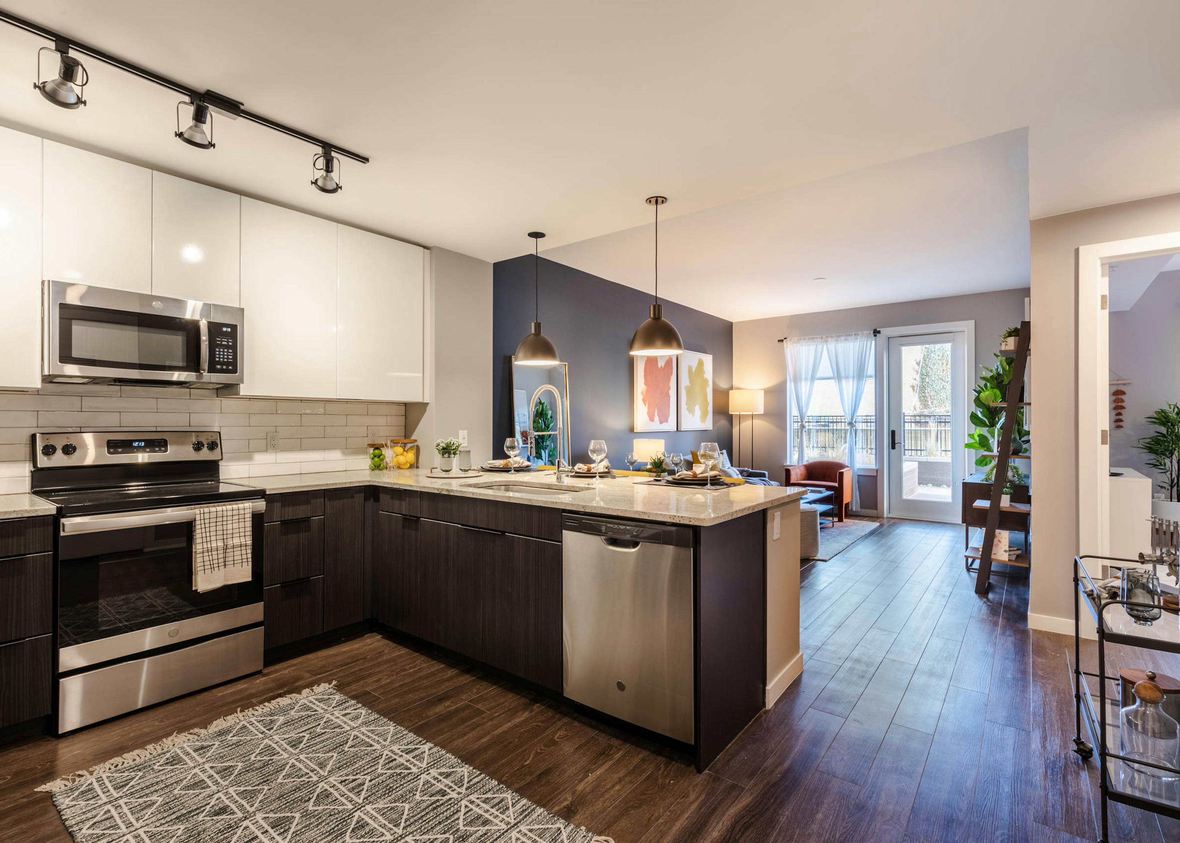 AMLI at Uptown living area with dark blue accent wall extending to eating area with view of modern kitchen in background