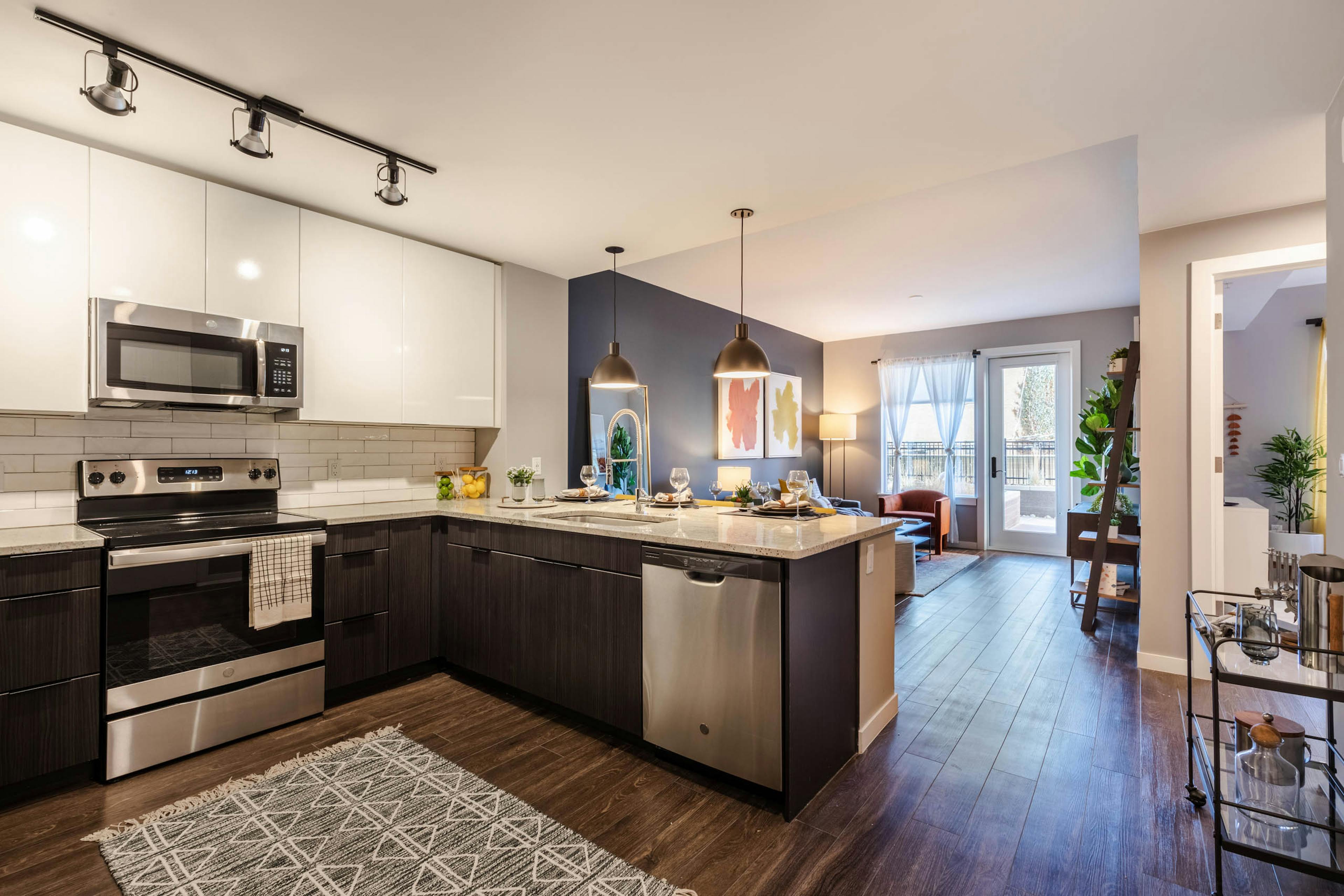 AMLI at Uptown living area with dark blue accent wall extending to eating area with view of modern kitchen in background