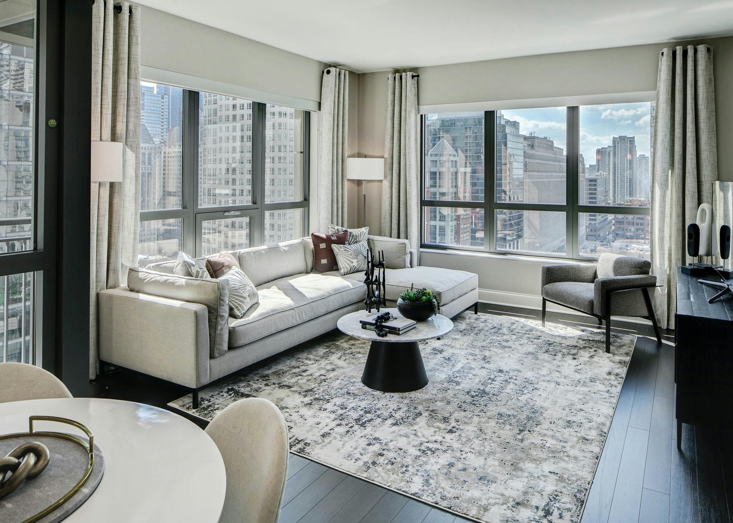 AMLI River North modern apartment living room with neutral furnishings lined with windows showing a vibrant city view
