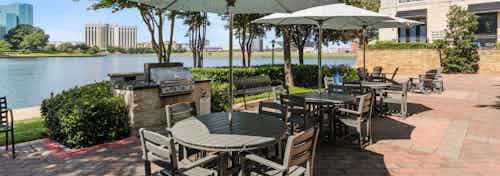 AMLI Las Colinas grilling and dining area shaded by three umbrellas with a view of Lake Carolyn and Las Colinas