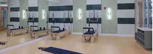 Yoga and Pilates studio at AMLI Evanston with light wood floors and only two exercise machines for maximal open space