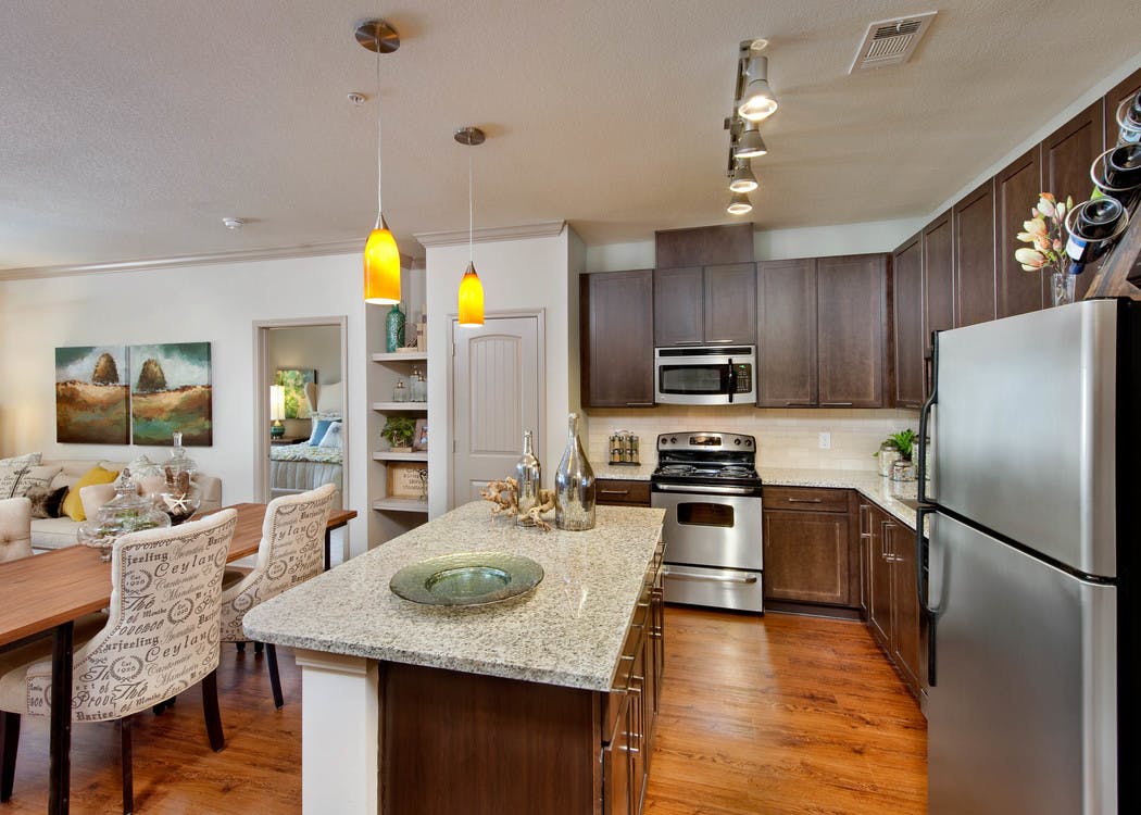 AMLI North Point kitchen with dark cabinets and granite countertops with a white backsplash and a spacious island