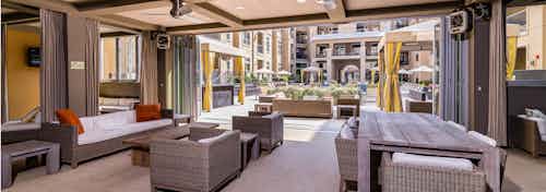 Daytime view of AMLI RidgeGate outdoor lounge with comfortable seating overlooking cabanas and pool area with lush planters