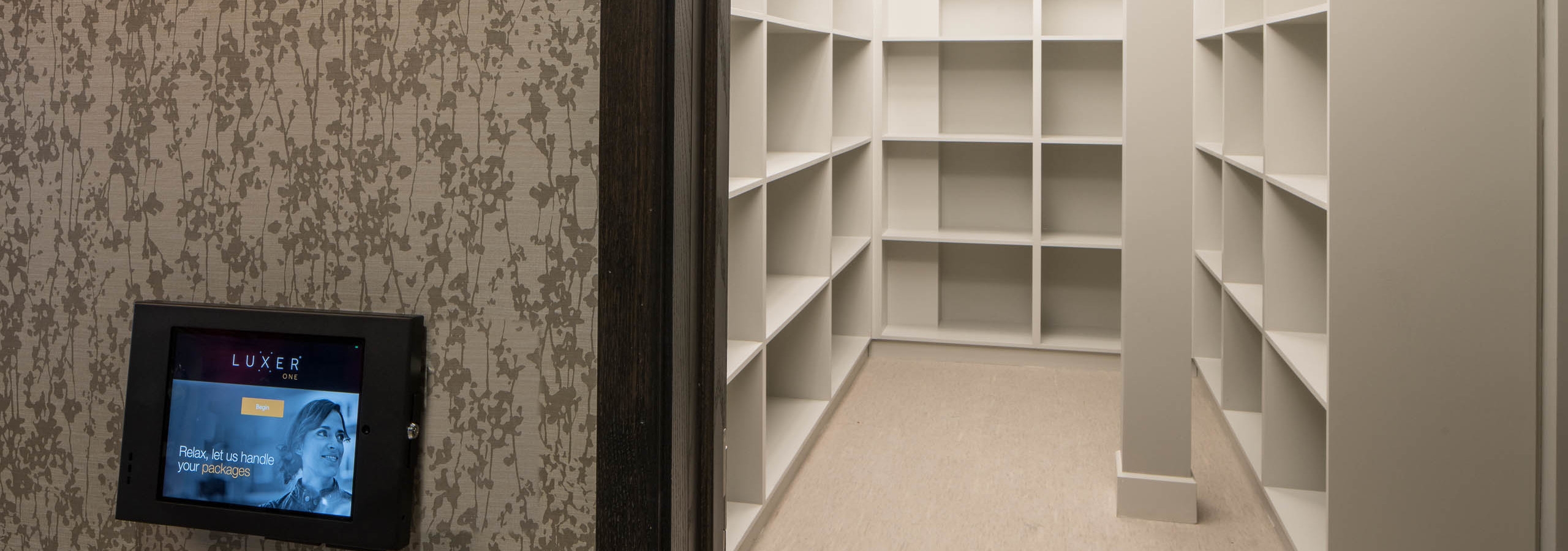 Interior of luxer package amenity at AMLI Deerfield with iPad on outside of doorway and wall to wall shelving inside room