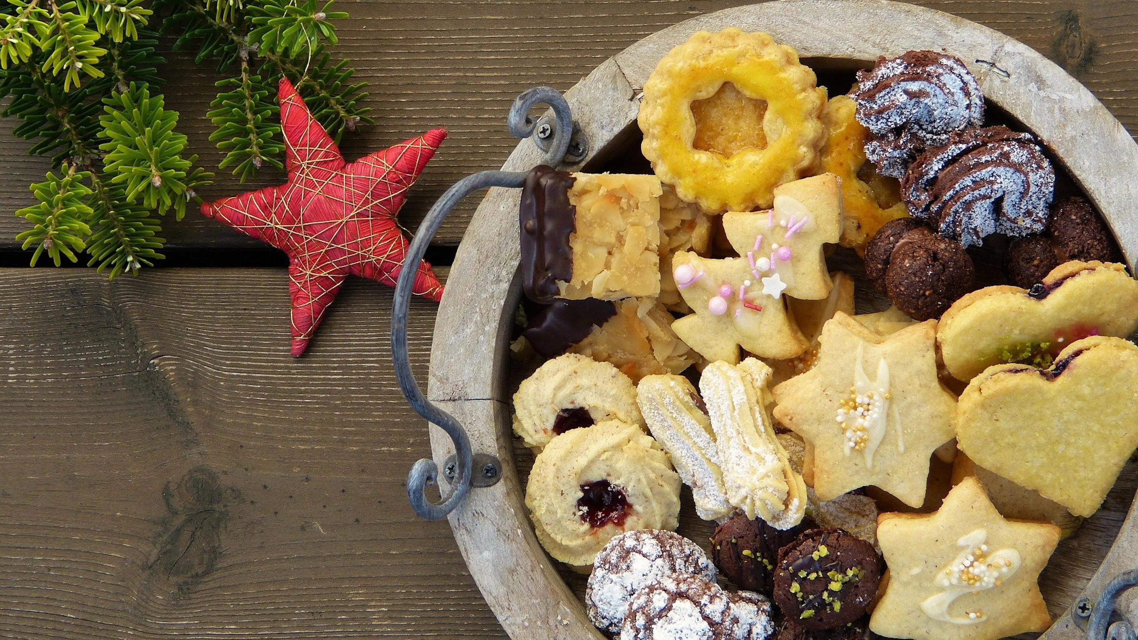 A wooden serving tray with an assortments of cookies in various shapes sizes and colors