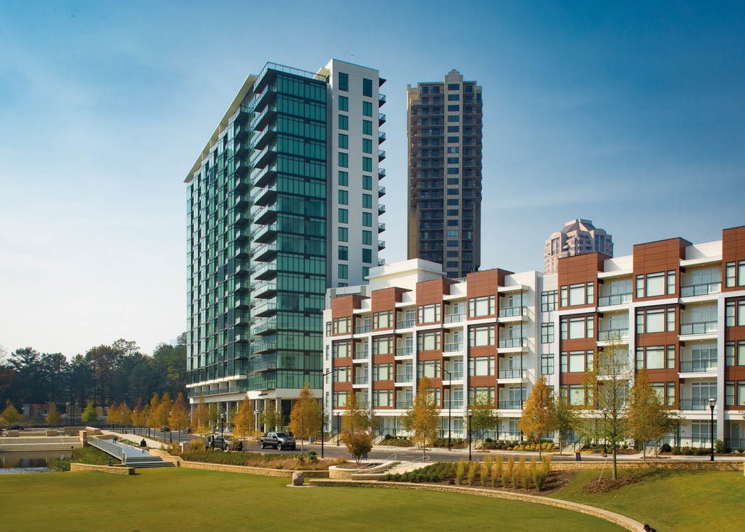 Exterior of the AMLI 3464 building in daylight with autumn trees lining the pavement and vibrant grass on the alternate side