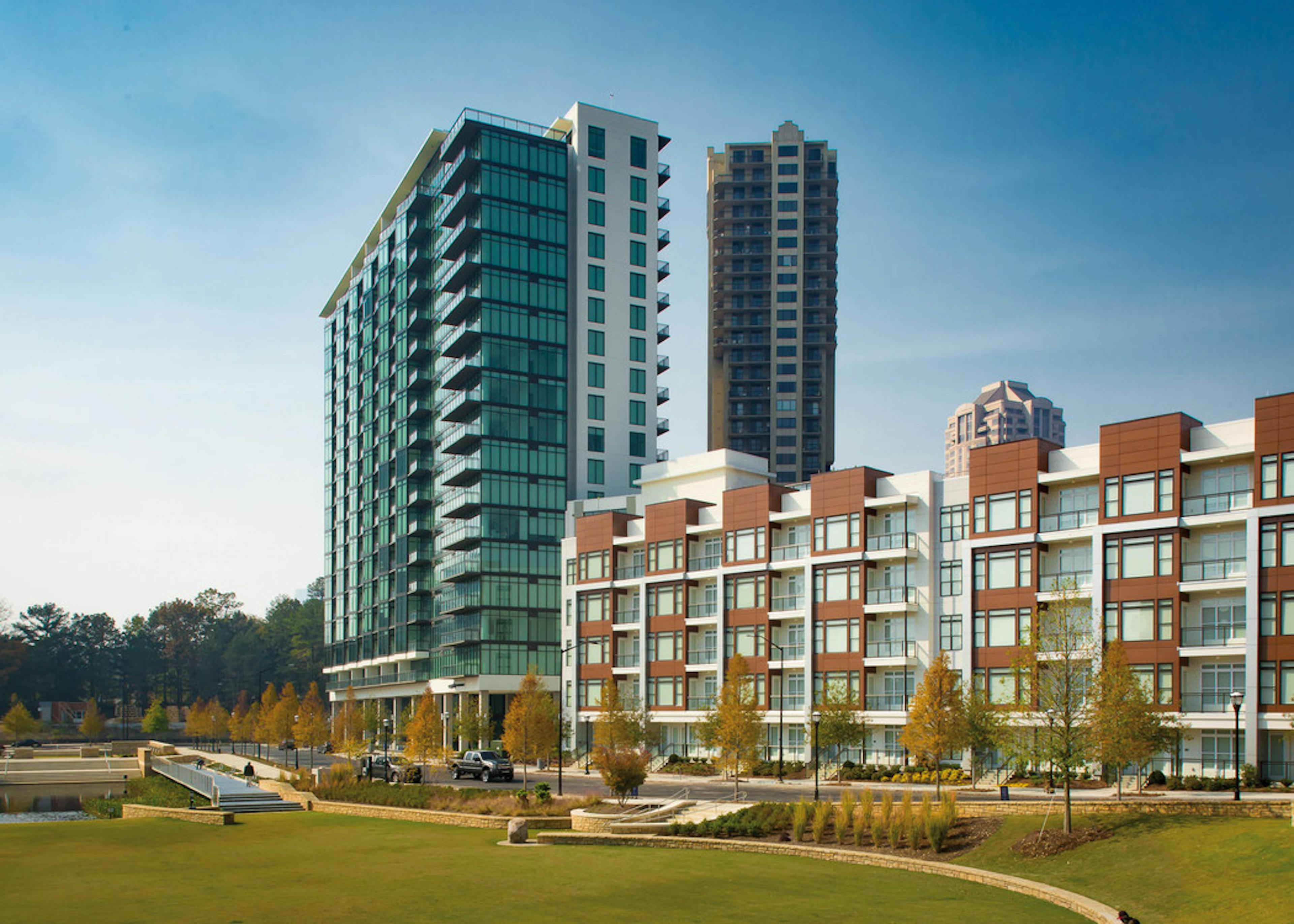 Exterior of the AMLI 3464 building in daylight with autumn trees lining the pavement and vibrant grass on the alternate side