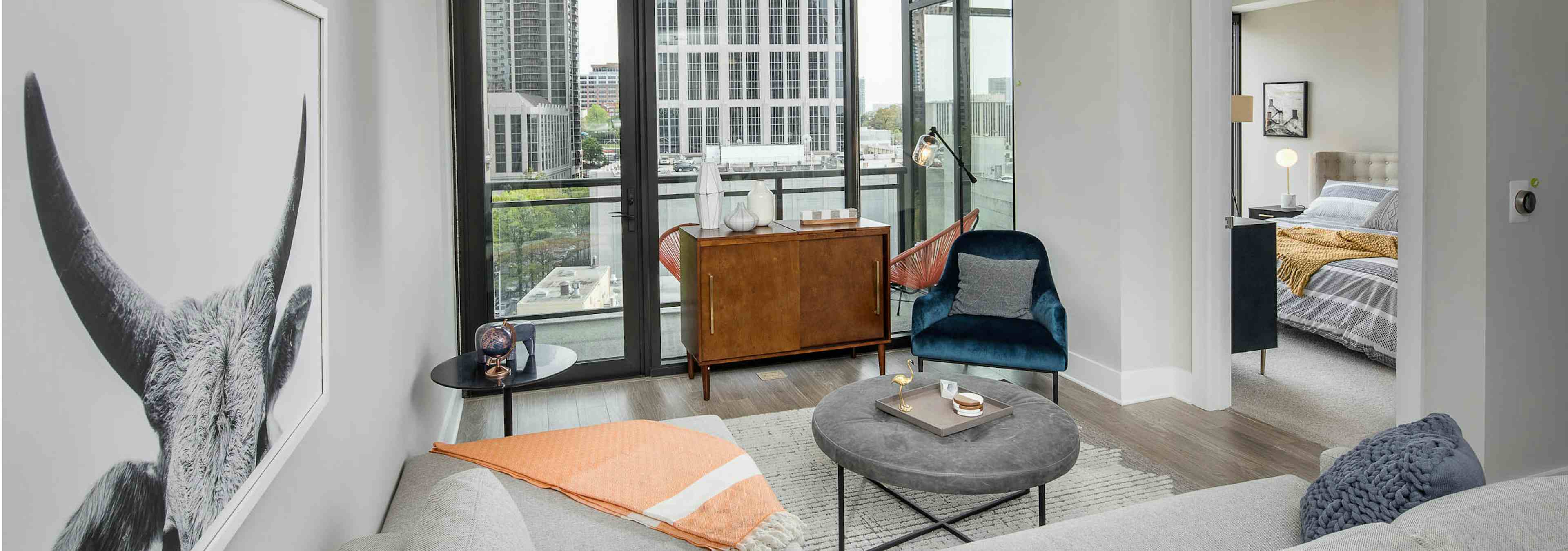 Living room at AMLI Arts Center with floor to ceiling windows overlooking the city and a large wall hanging of a ram