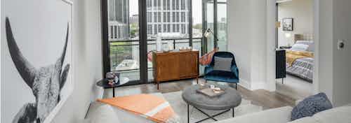 Living room at AMLI Arts Center with floor to ceiling windows overlooking the city and a large wall hanging of a ram