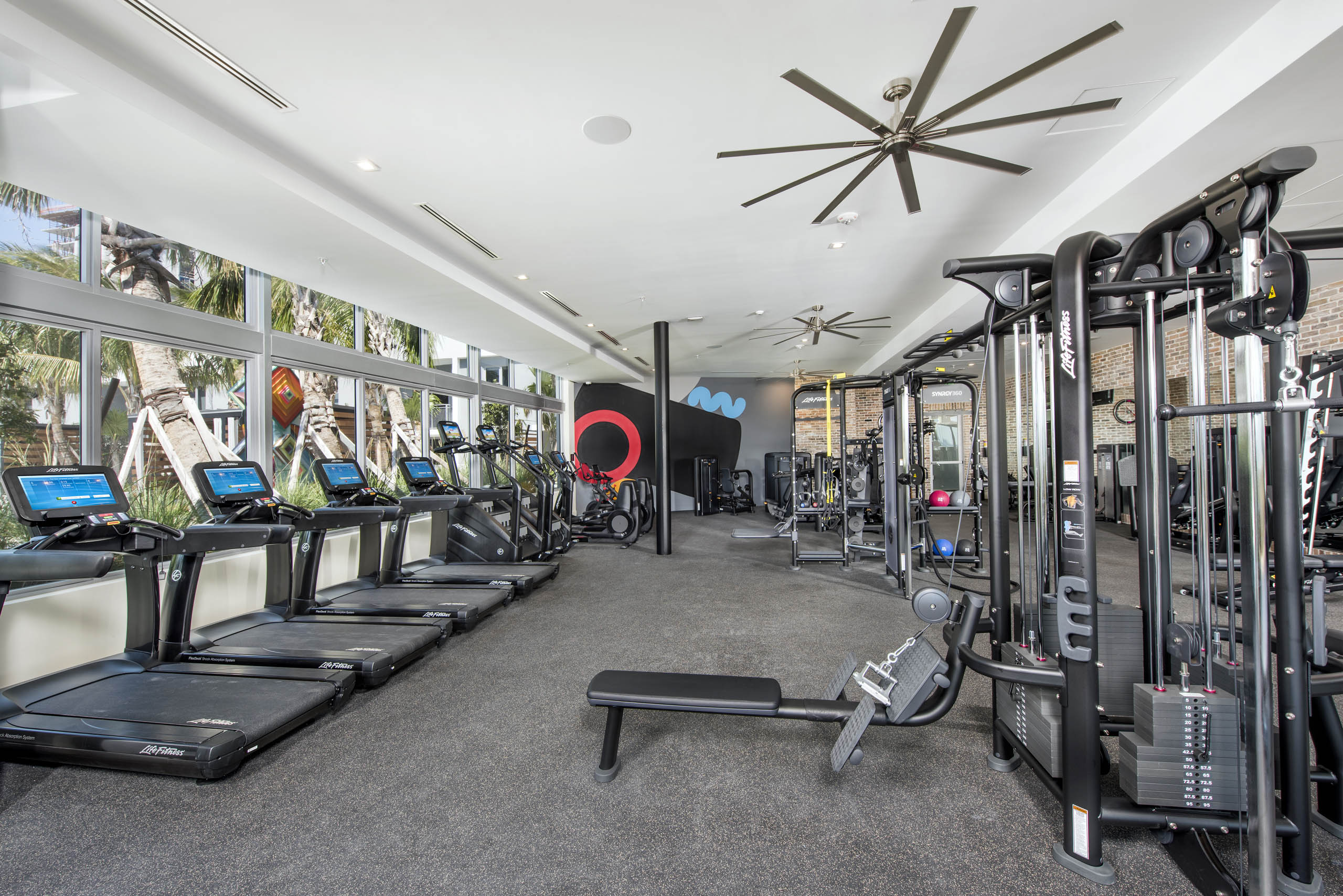 AMLI Midtown 29 fitness center with treadmills on window wall with mirror wall and weightlifting equipment and ceiling fans
