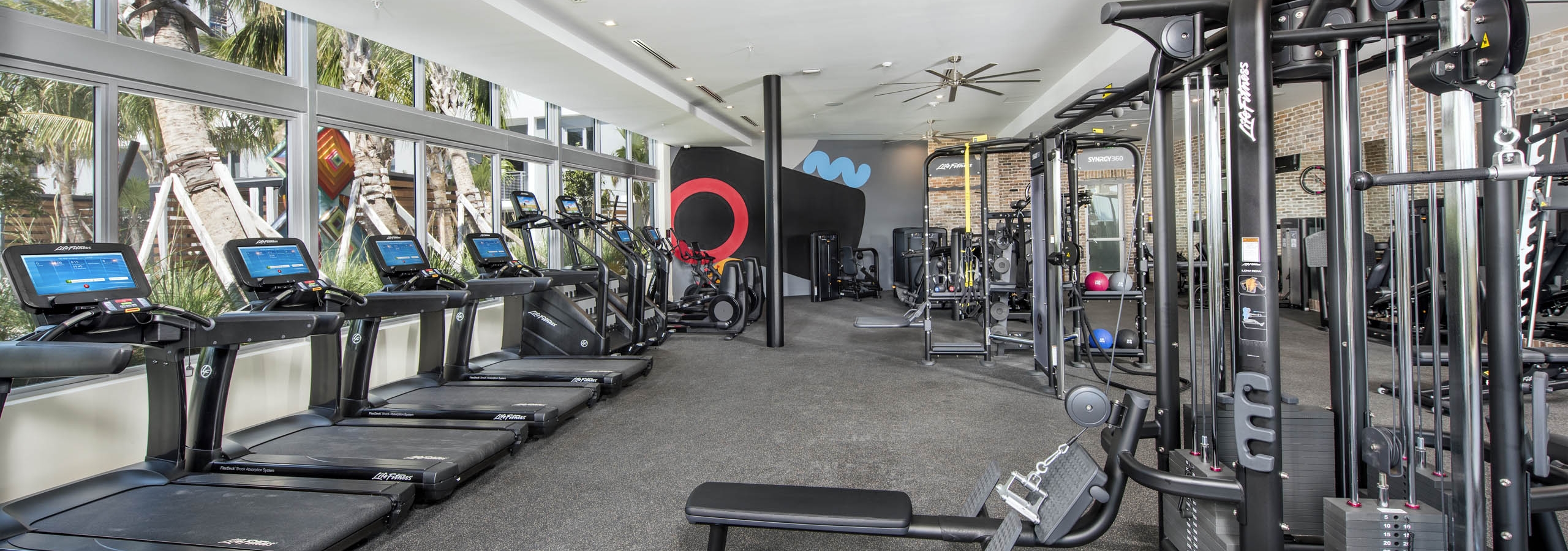 AMLI Midtown 29 fitness center with treadmills on window wall with mirror wall and weightlifting equipment and ceiling fans