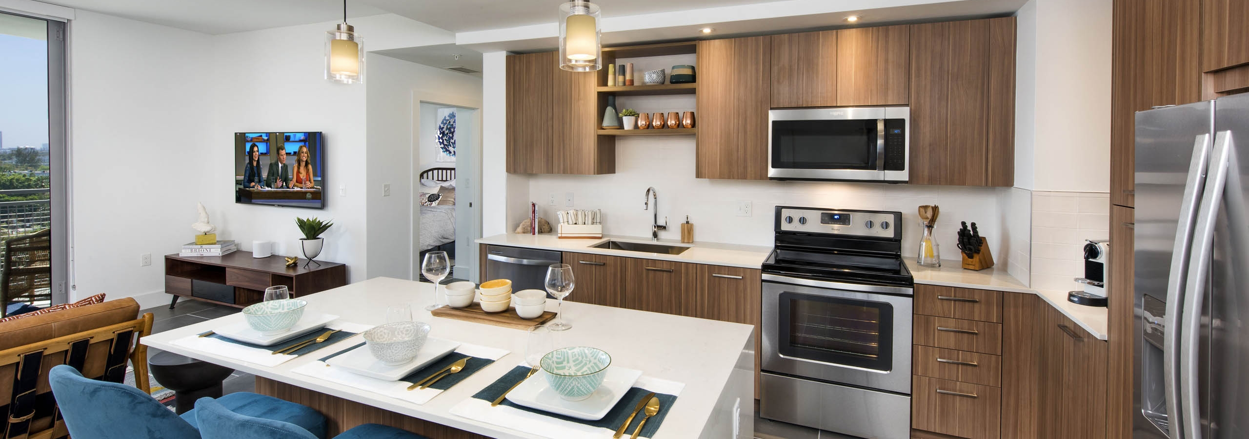 Interior kitchen with white island and blue chairs with pendant lighting and wood cabinets at AMLI Midtown 29 apartments