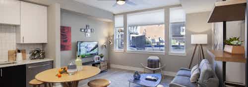Interior view of AMLI Riverfront Green apartment kitchen and living room with window view of adjacent brick building