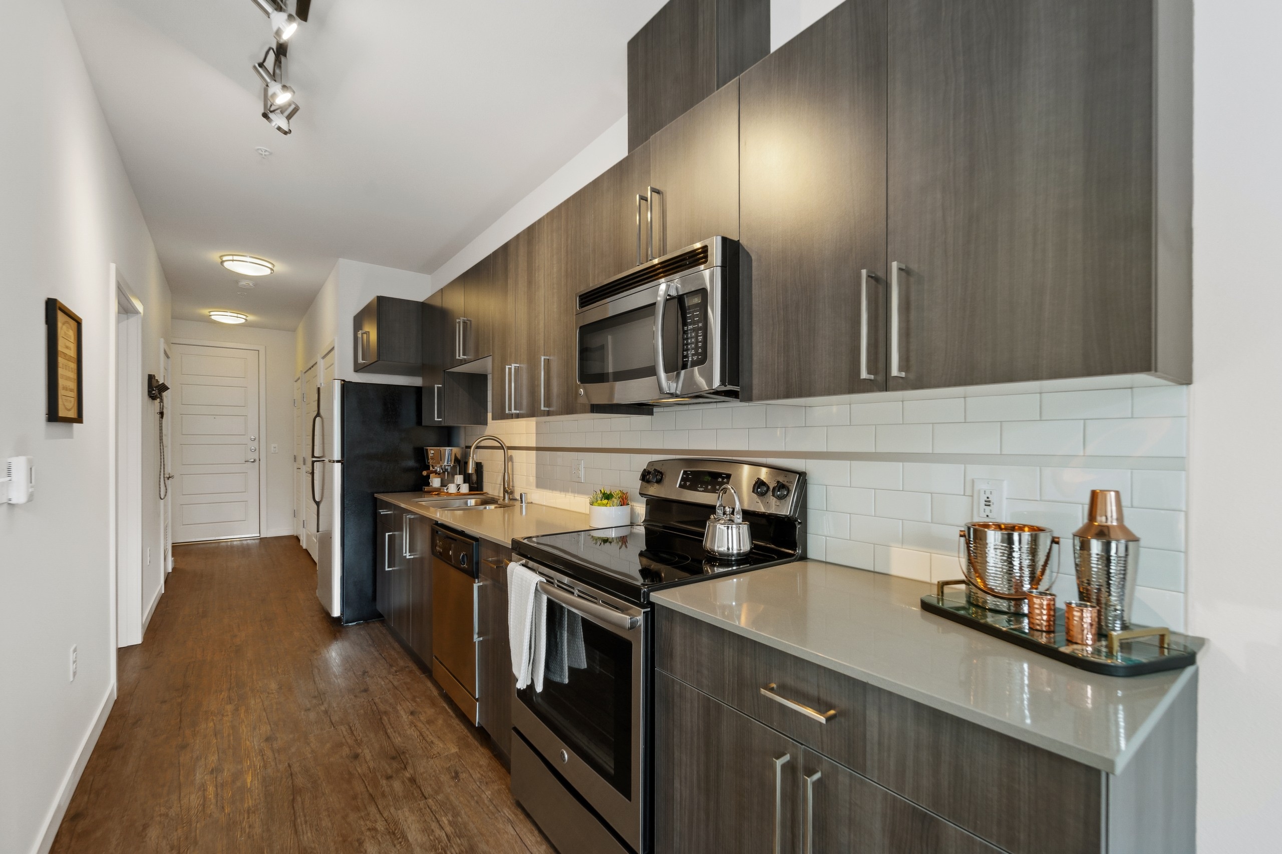 AMLI South Lake Union apartment kitchen with wood grain cabinets and stainless appliances as well as a view of the front door