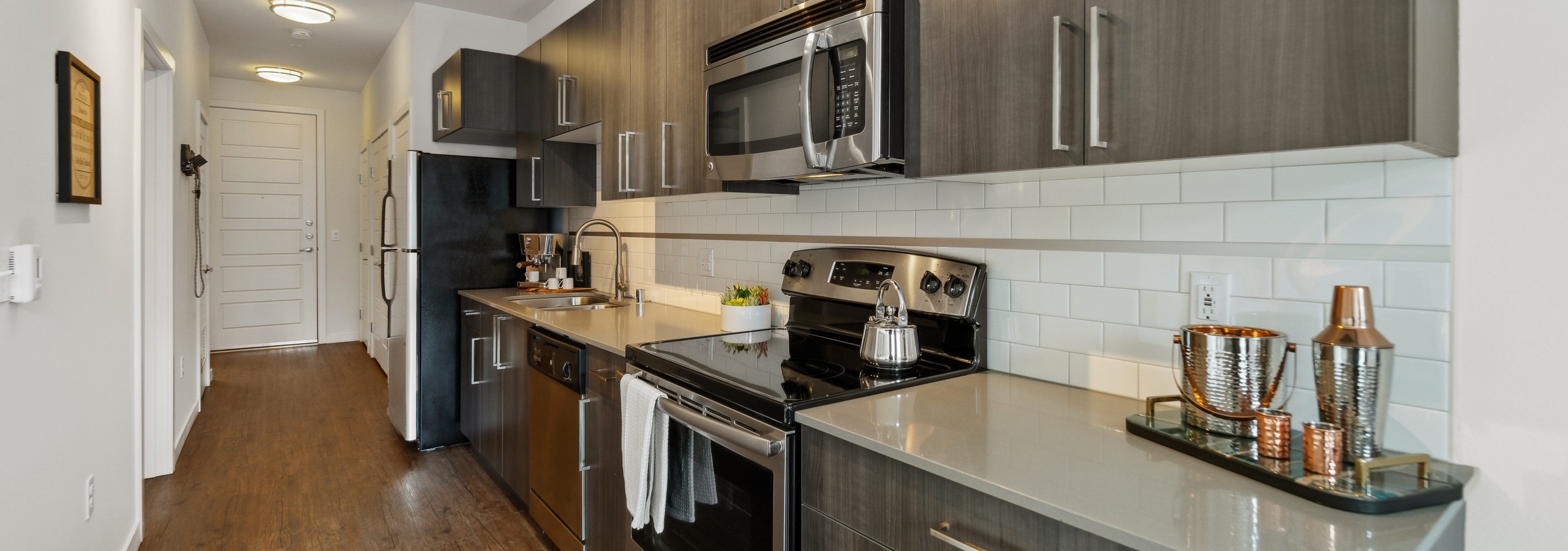 AMLI South Lake Union apartment kitchen with wood grain cabinets and stainless appliances as well as a view of the front door
