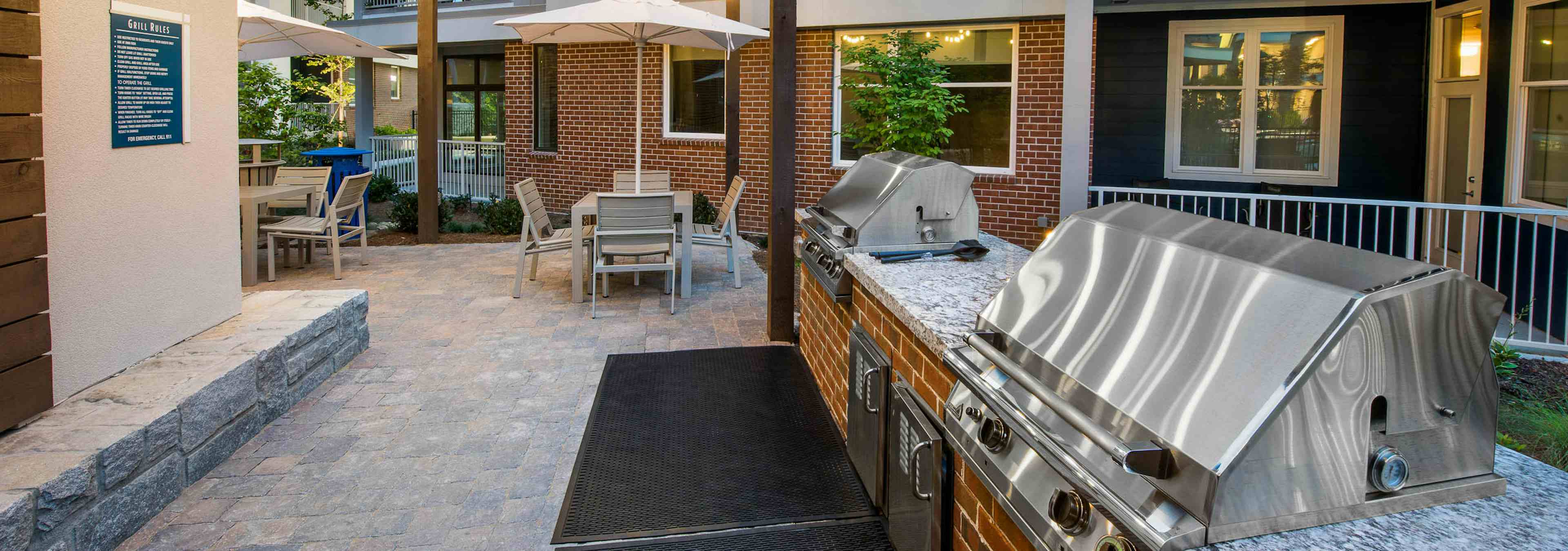 AMLI Buckhead barbecue area with grills and outdoor counter space and stone flooring leading to area with tables and chairs