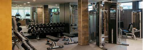 View of fitness center at AMLI Riverfront Green apartments with free weights and other strength training machines