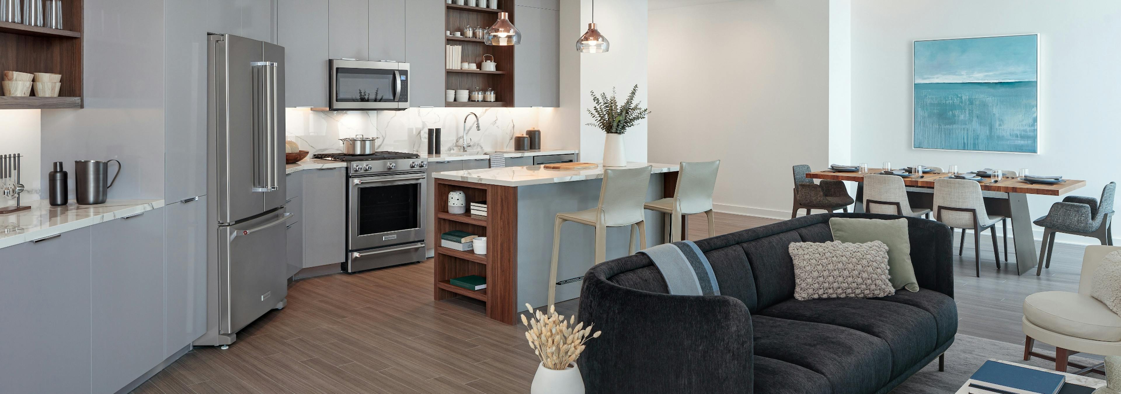 AMLI Fountain Place living room with a black couch and grey island kitchen and dining area visible in the background 