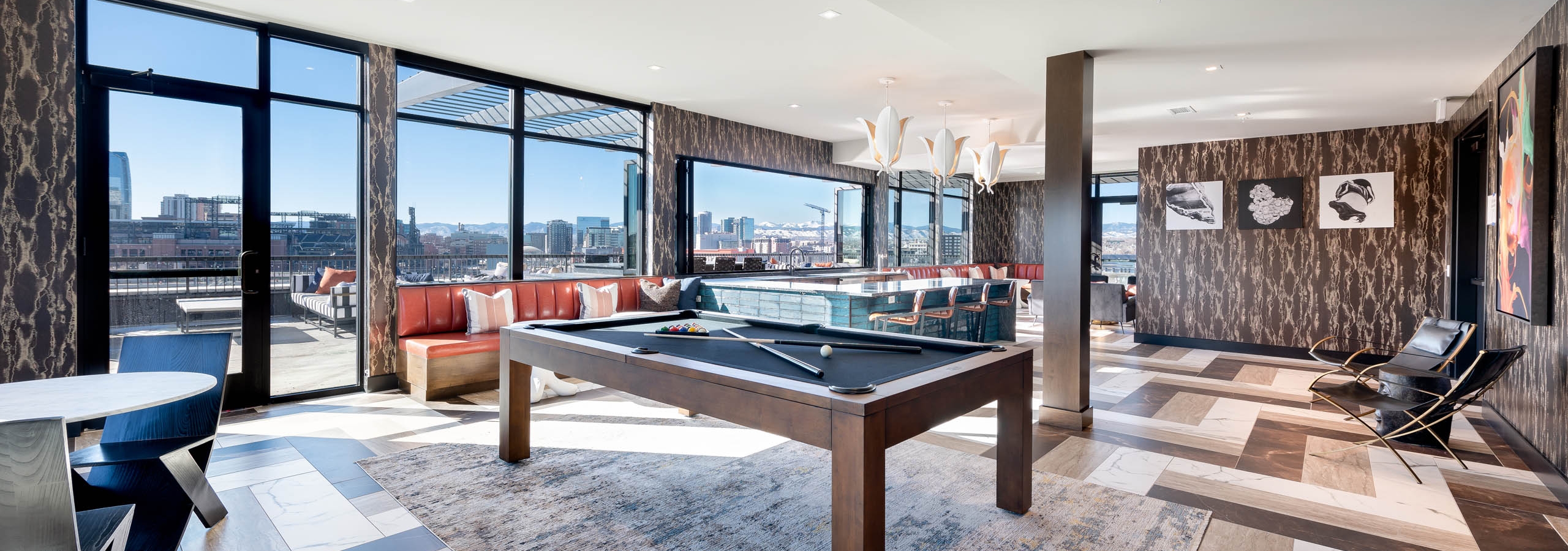 Interior view of a resident sky lounge at AMLI Art District with a pool table and bar area and a view of downtown Denver