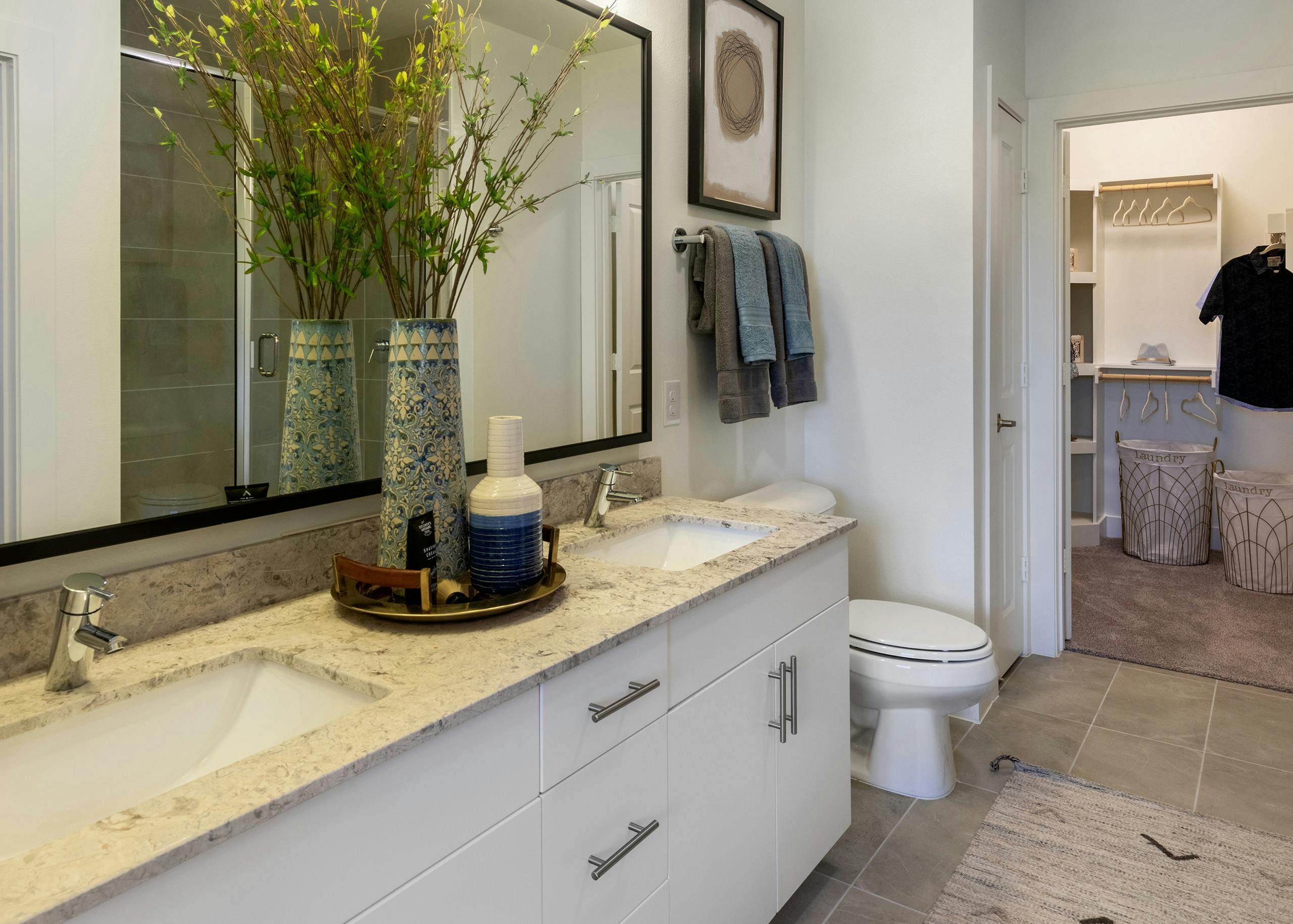 Interior view of AMLI Grapevine apartment bathroom with white granite countertops and a double vanity and a walk-in closet