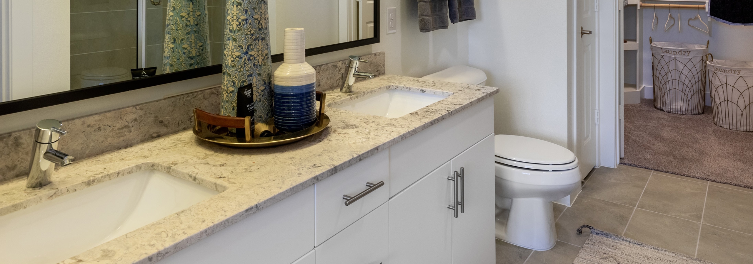 Interior view of AMLI Grapevine apartment bathroom with white granite countertops and a double vanity and a walk-in closet