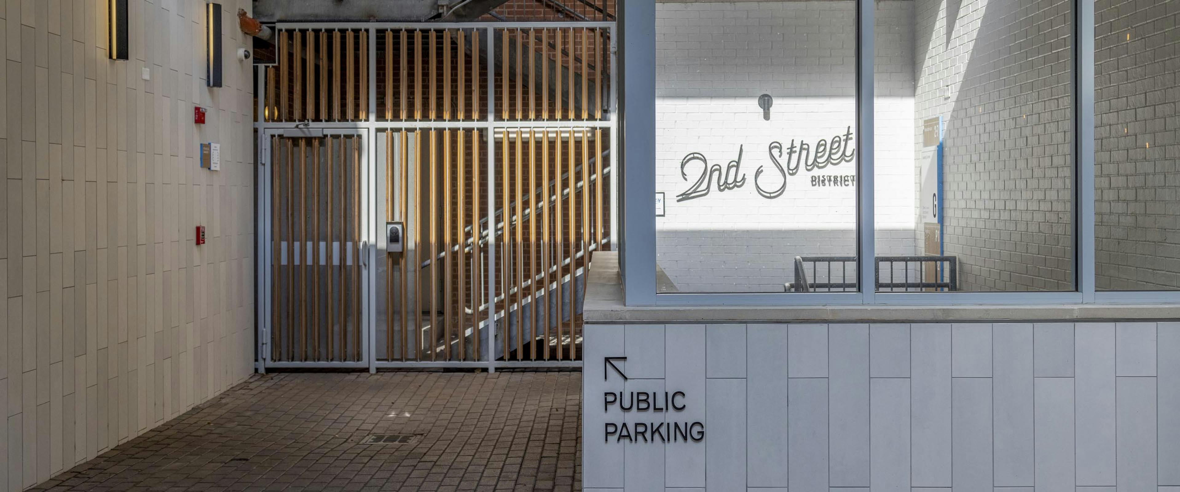 View of AMLI Downtown public garage and building access stairwell with a 2nd Street District sign illuminated by the sun