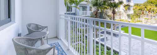 Exterior view of AMLI Park West apartment balcony with white metal bars and gray table and 2 chairs and a view of courtyard