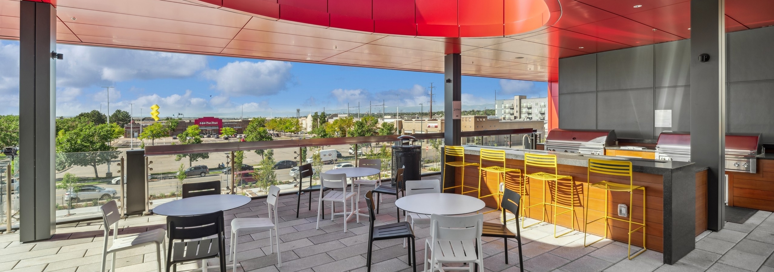 Rooftop with orange ceiling over two stainless steel outdoor grills surrounded by outdoor seating at AMLI Broadway Park