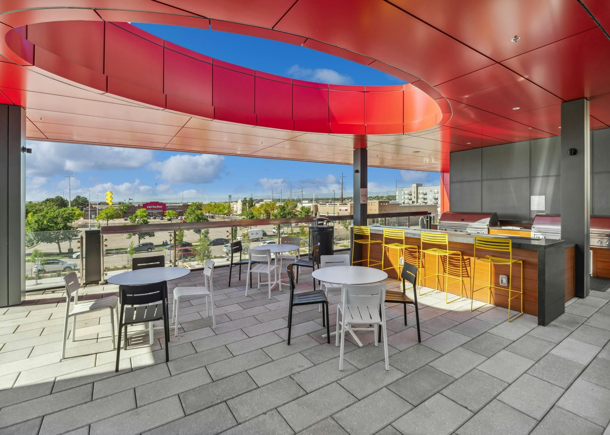 Rooftop with orange ceiling over two stainless steel outdoor grills surrounded by outdoor seating at AMLI Broadway Park