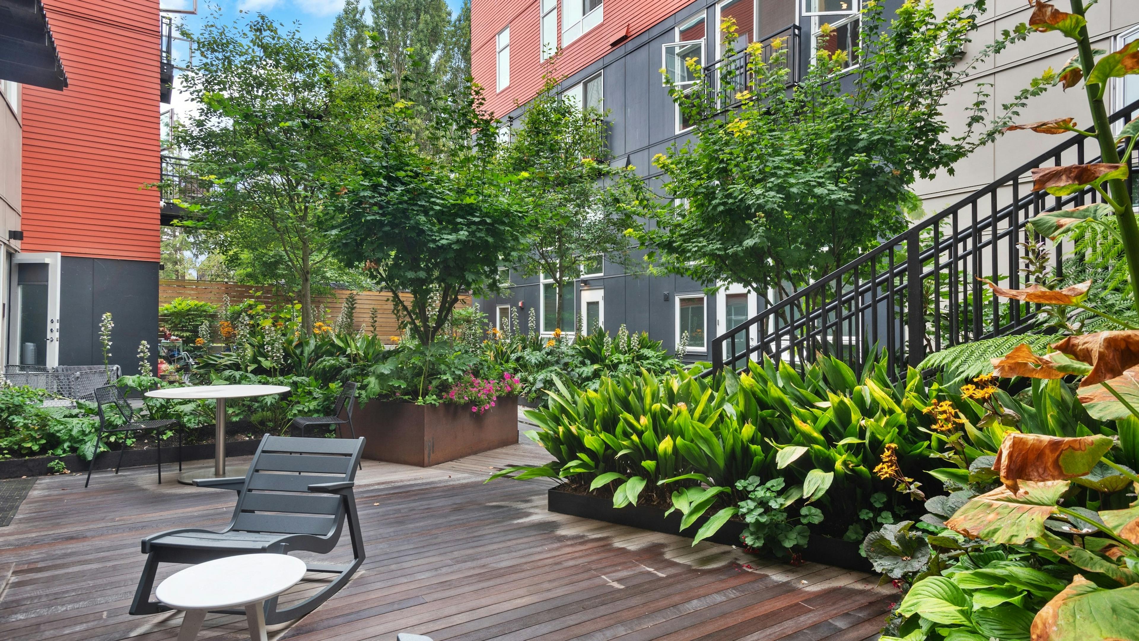 Exterior view of a courtyard garden at AMLI Wallingford apartments with tables and chairs and green plants and trees