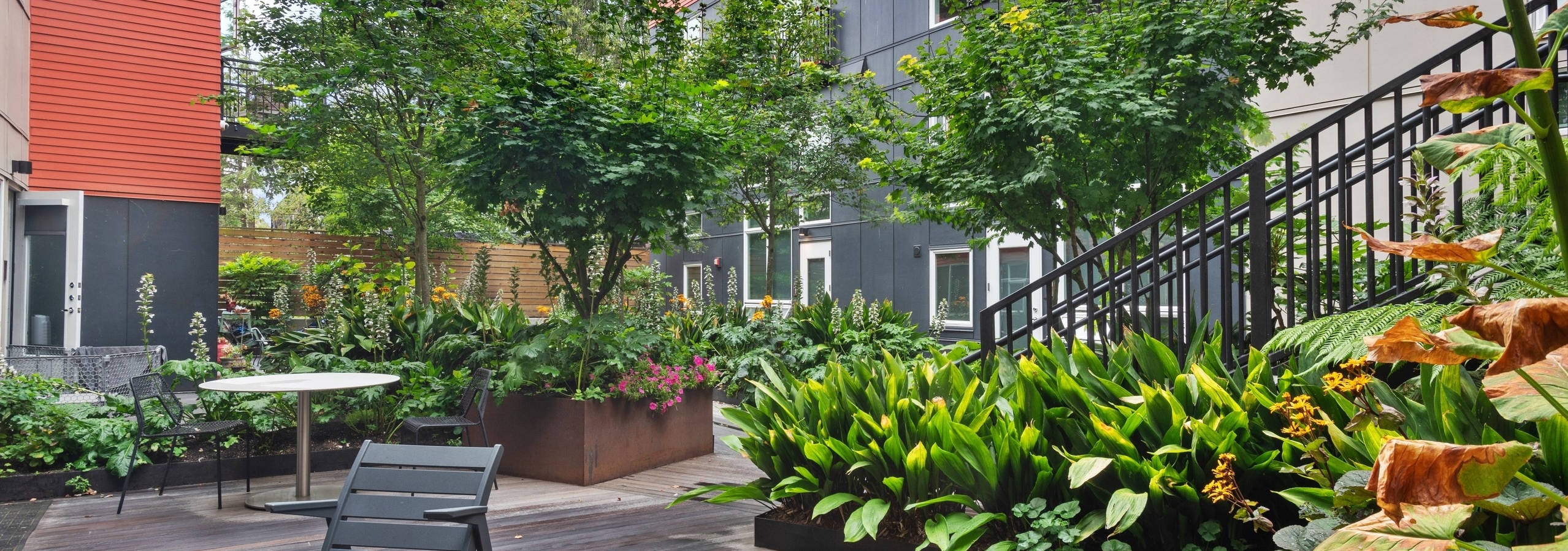 Exterior view of a courtyard garden at AMLI Wallingford apartments with tables and chairs and green plants and trees