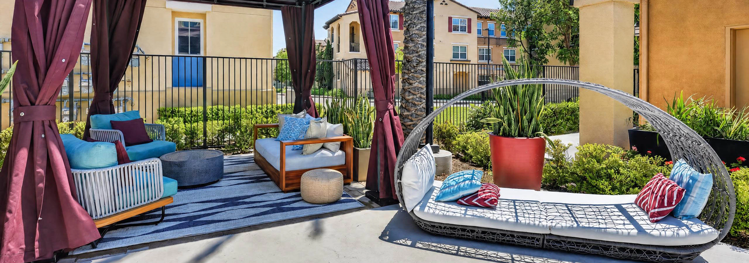 Poolside shaded cabana lounge seating at AMLI Camarillo apartments with cushioned daybed, palm tree and landscaped courtyard.