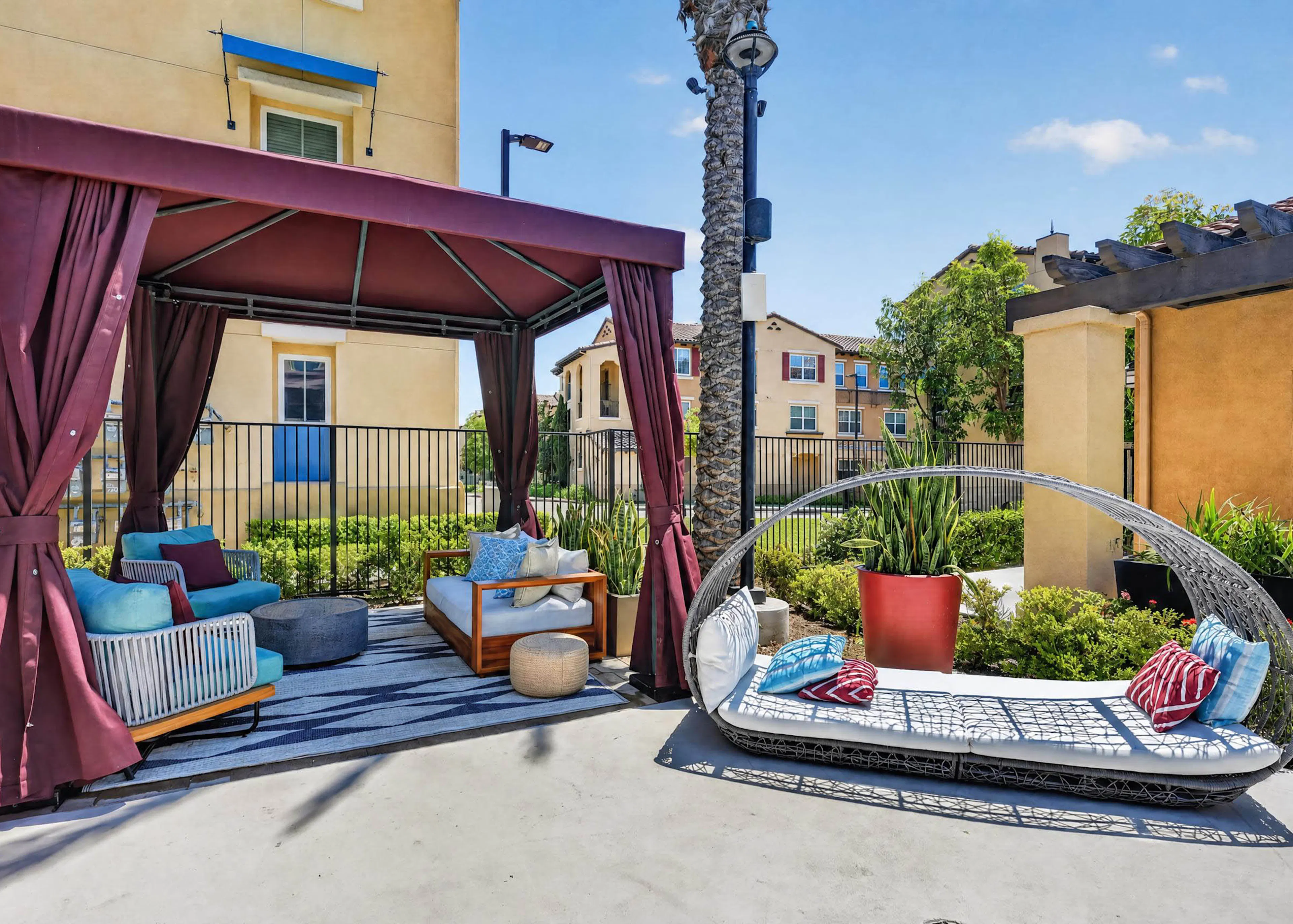 Poolside shaded cabana lounge seating at AMLI Camarillo apartments with cushioned daybed, palm tree and landscaped courtyard.