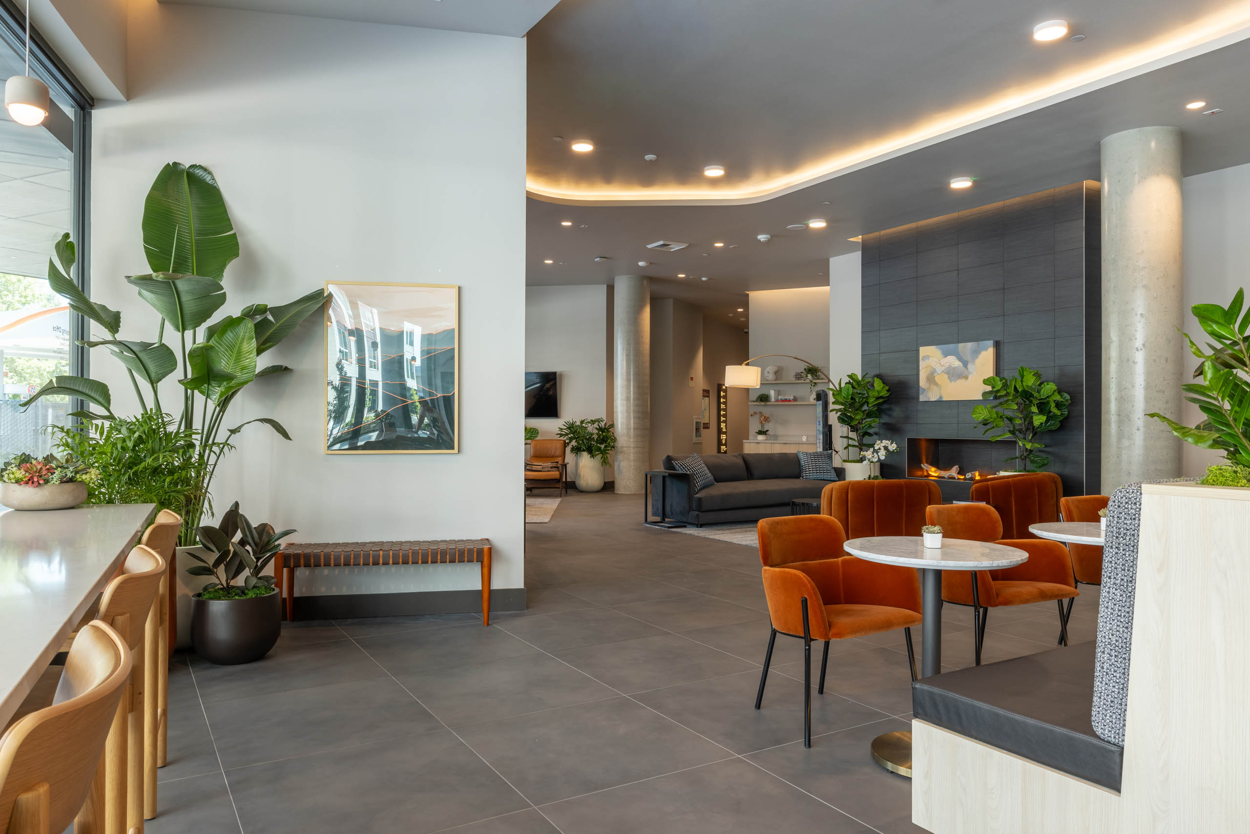 East Building lobby with seating areas, a fireplace lounge, artwork, and greenery throughout the open, modern space.